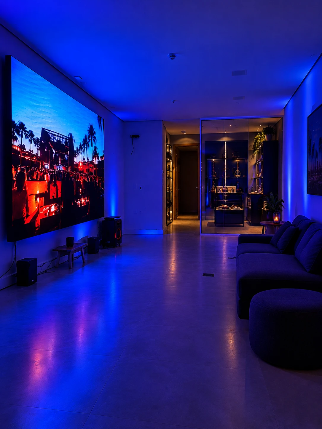 Telão de LED exibindo um show no lounge, com sofá e vitrine iluminada